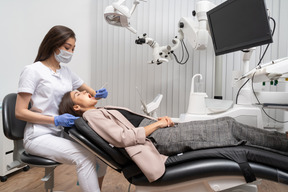 Full-length of a female dentist examining her female patient lying in a hospital cabinet