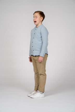Cute boy with open mouth standing in profile