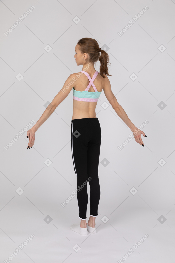 Three-quarter back view of teen girl standing with her arms outstretched