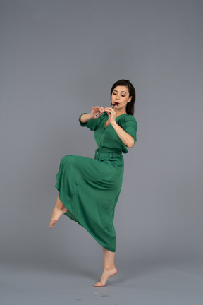 플루트 연주 녹색 드레스에 춤추는 젊은 아가씨의 측면보기