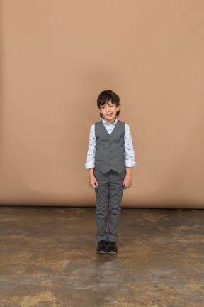 Front view of a cute boy in suit looking at camera and making faces