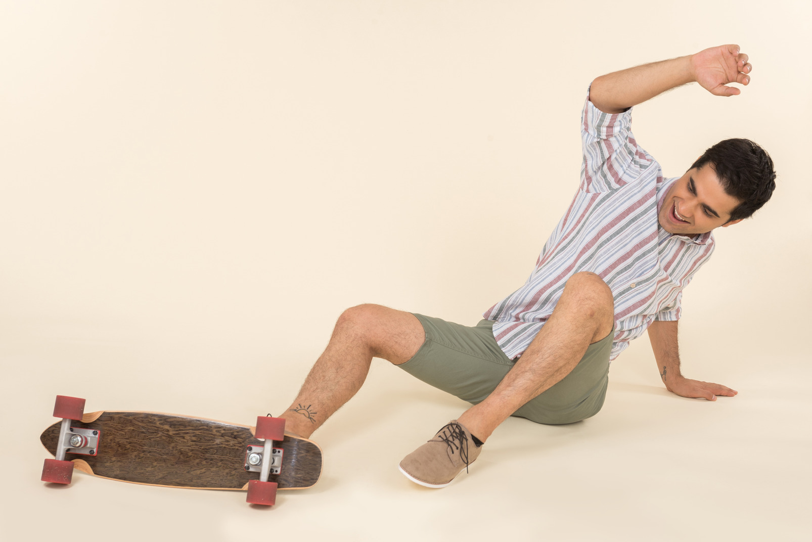 A nice-looking caucasian guy in a striped t-shirt, having fun learning how to ride a skateboard