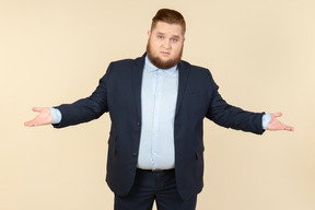 Junger übergewichtiger mann im anzug, der okaygeste mit beiden händen zeigt