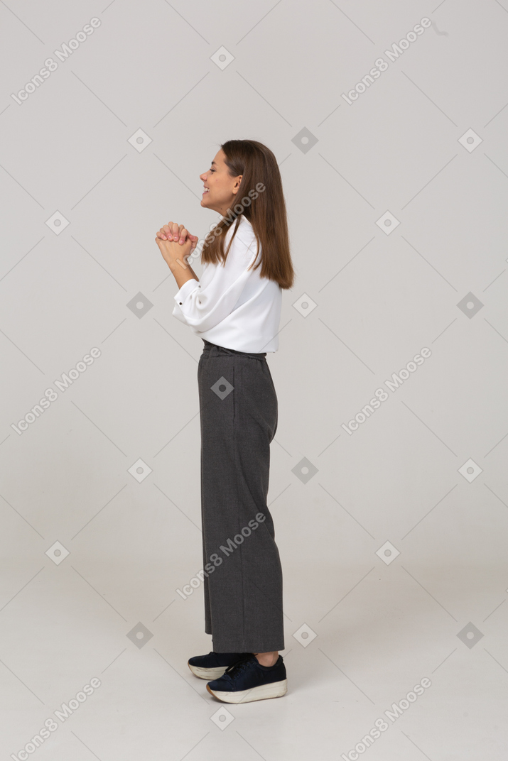 Vista lateral de uma jovem satisfeita com roupa de escritório, de mãos dadas