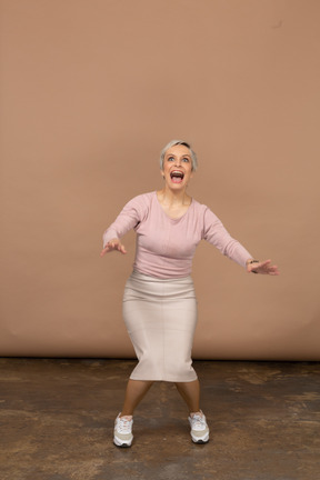 Vista frontal de una mujer impresionada en ropa casual en cuclillas y estirando los brazos