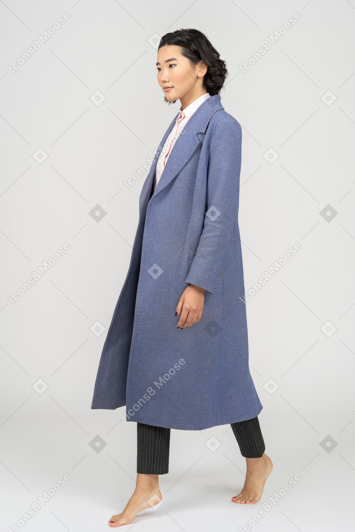 Mujer joven con abrigo caminando de puntillas