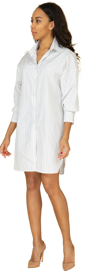 Трехчетвертный вид уверенной в себе темнокожей молодой девушки в белом платье