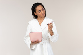 Black woman in white bathrobe going about her morning routine