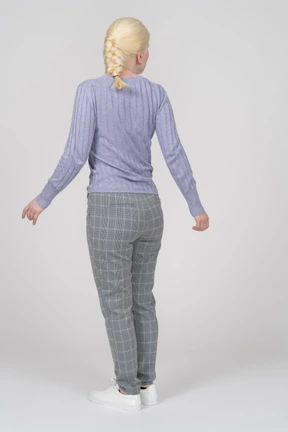Back view of a young woman standing with arms at sides