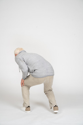 Back view of man bending over and holding his hands on his knee