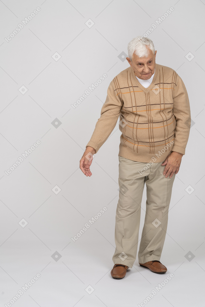 Front view of an old man in casual clothes standing with extended arm