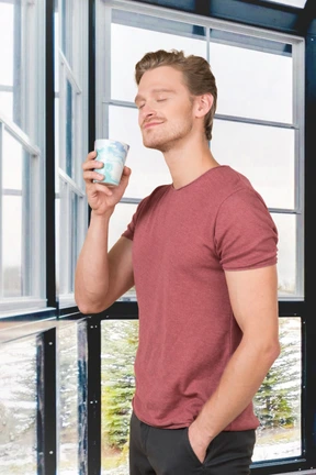 A man standing in front of a window holding a cup