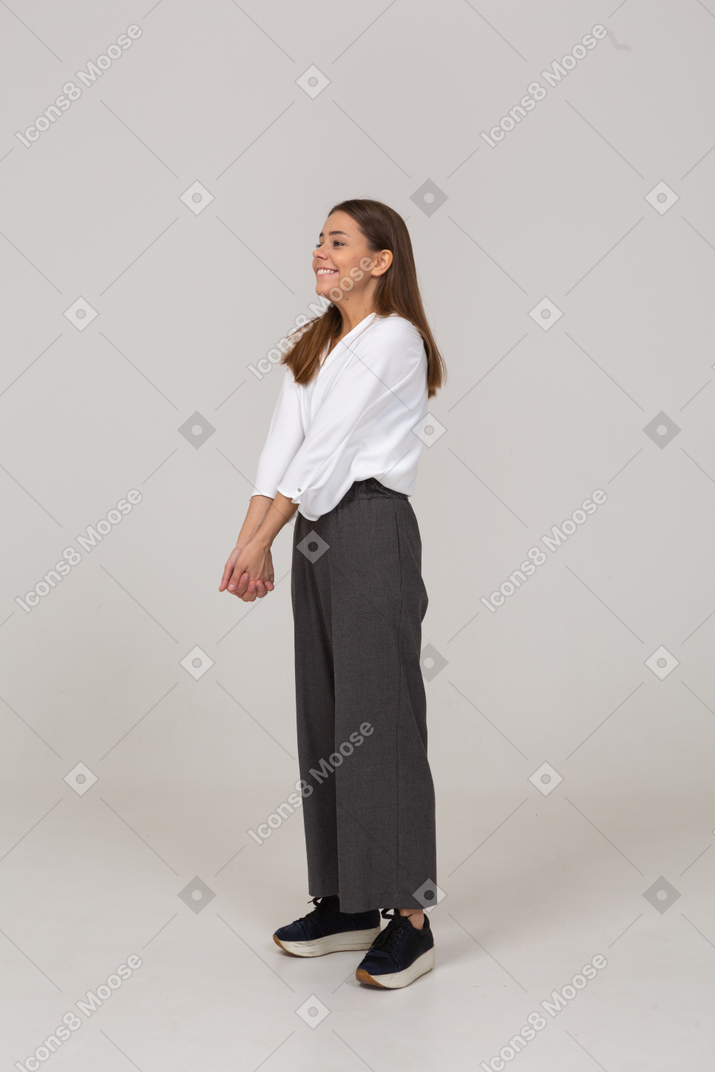 Vista di tre quarti di una giovane donna sorridente in abiti da ufficio che si tiene per mano insieme