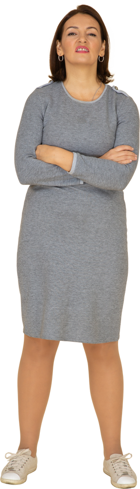 一个穿着灰色连衣裙的女人双臂交叉站立的前视图