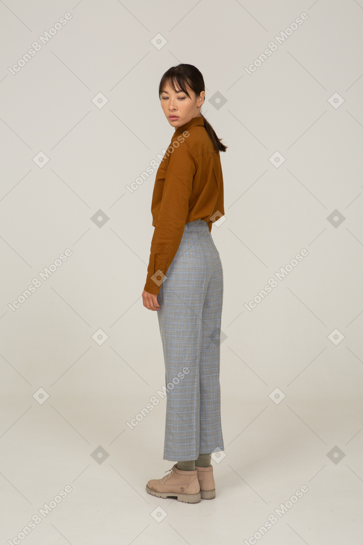 Three-quarter back view of a young asian female in breeches and blouse turning away