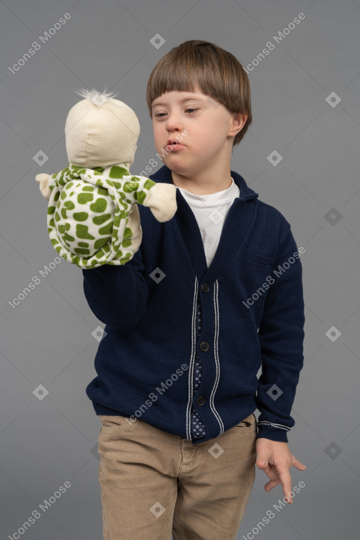 Little boy talking to a tortoise puppet