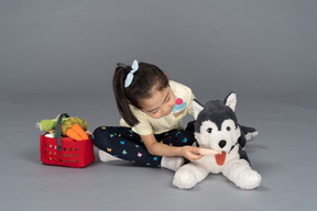 Ritratto di una bambina che dà da mangiare a un cane di peluche
