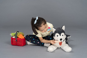 Retrato de una niña alimentando a un perro de peluche