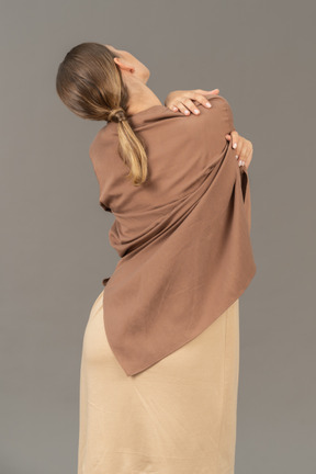 Vista traseira de uma mulher tirando a roupa por cima do ombro