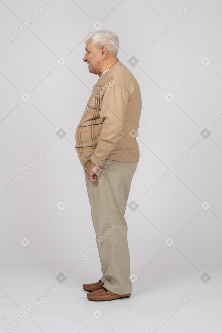 一位身穿休闲服、双手插在口袋里站着的老人的侧视图