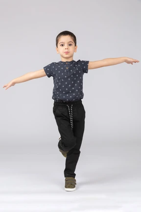 Front view of a cute boy balancing on one leg and outstretching arms