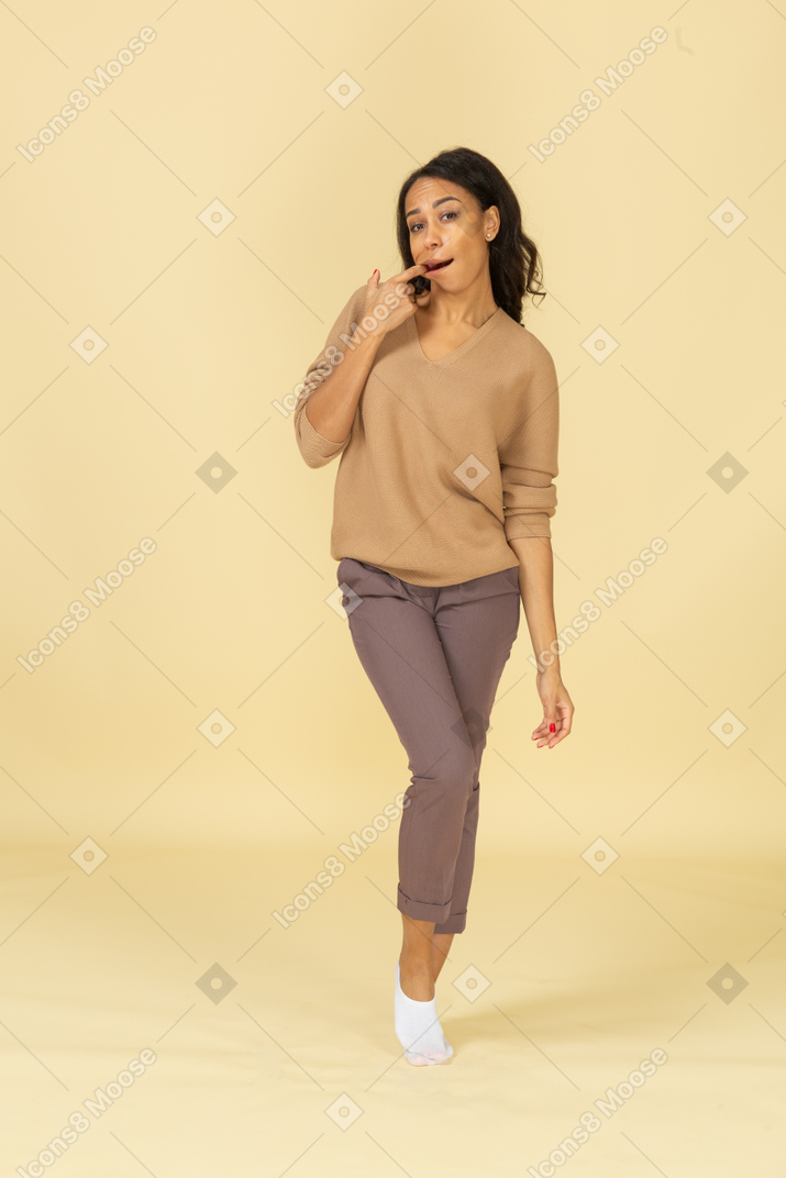 Вид спереди забавной темнокожей молодой женщины, вставляющей палец в рот