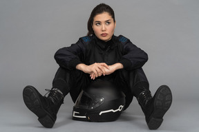 Uma jovem confiante, sentada com um capacete entre as pernas