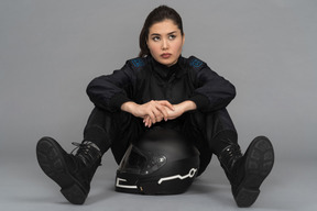 A self-confident young woman sitting with a helmet between her legs