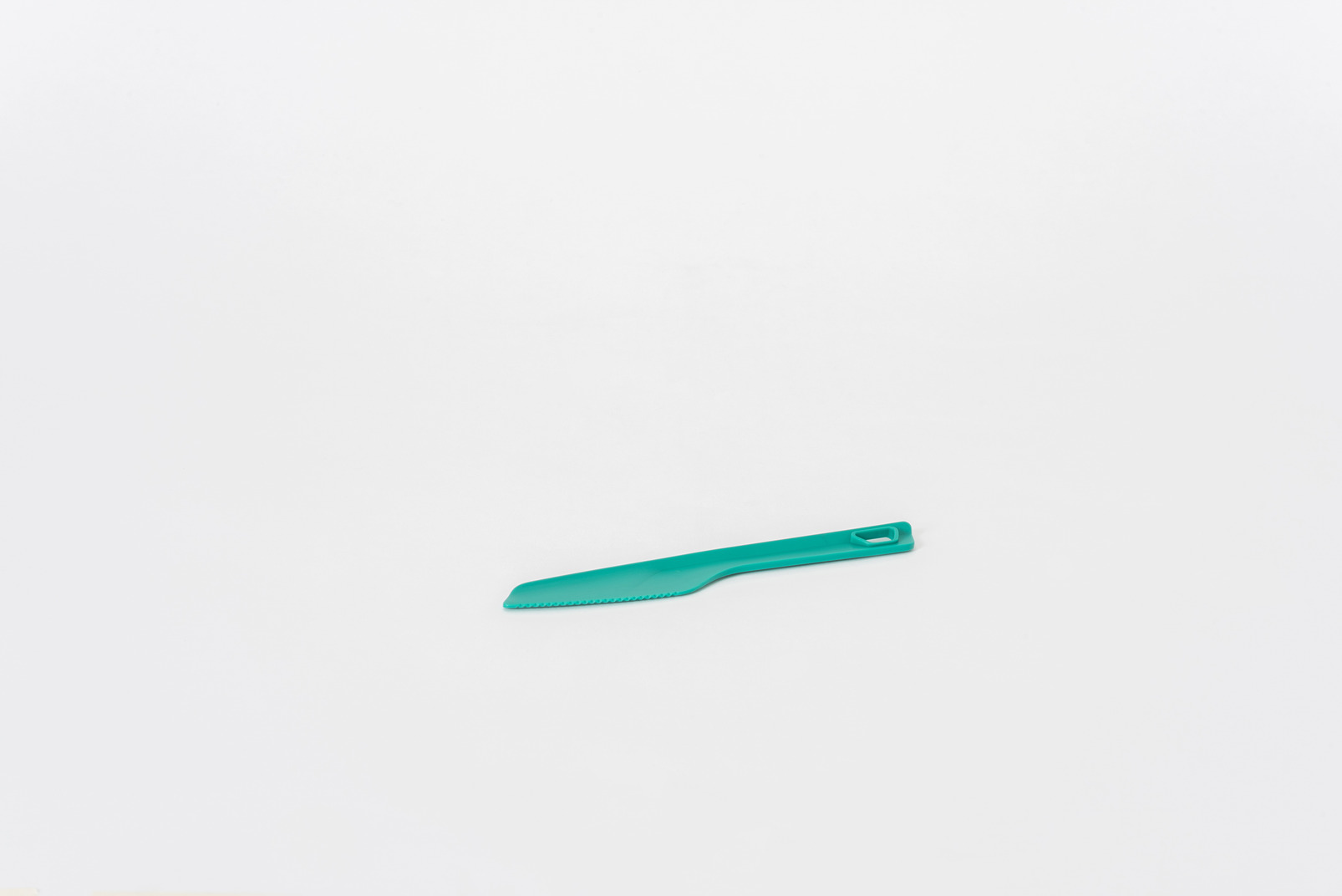 Plastic green kitchen knife on a white background