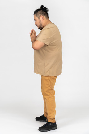 Plump asian man keeps palms pressed together in supplication
