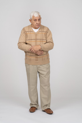 Vue de face d'un vieil homme en vêtements décontractés regardant quelque chose avec intérêt