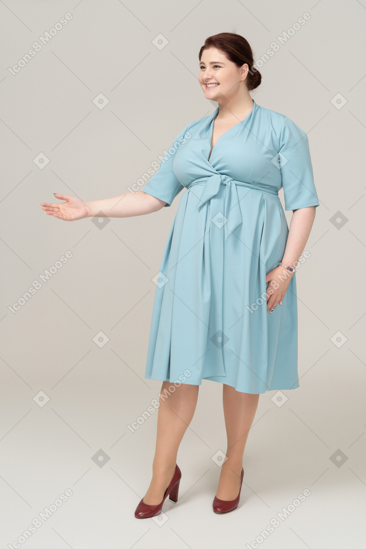 Vista lateral de uma mulher de vestido azul cumprimentando alguém