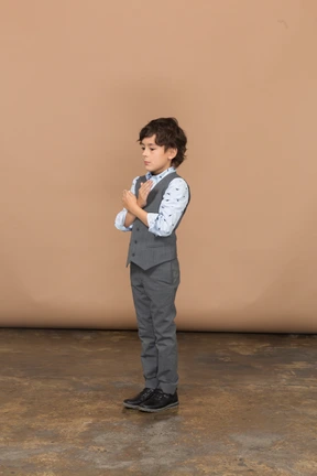 Side view of a boy in grey suit showing stop gesture
