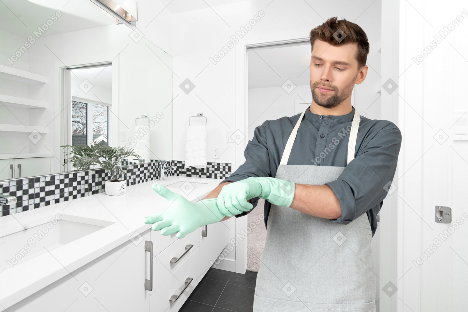 A man in an apron wearing gloves in a bathroom