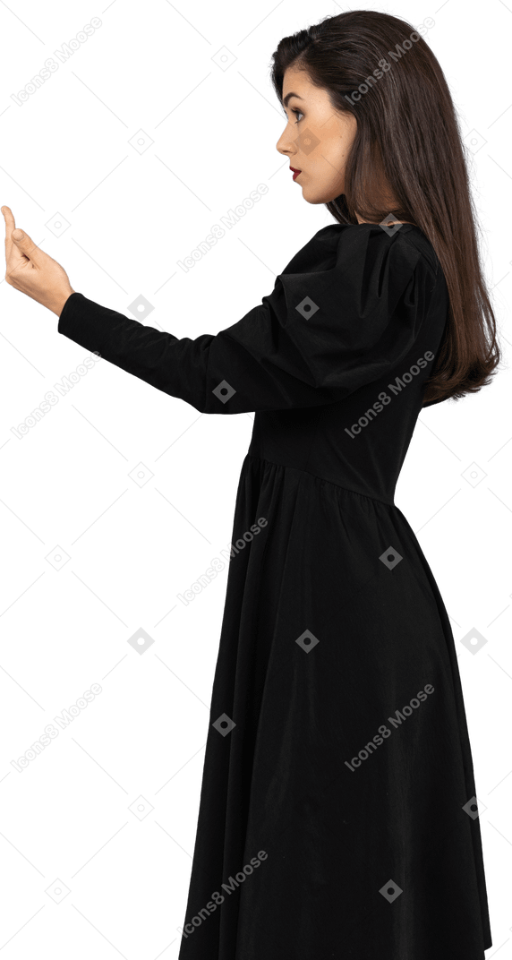 Вид сбоку молодой леди в черном платье показывает средний палец