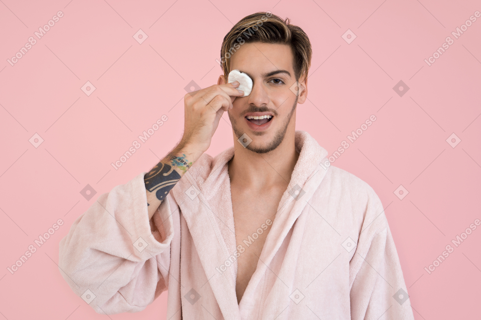 Handsome guy doing his beauty routine and closing one eye with a cotton pad
