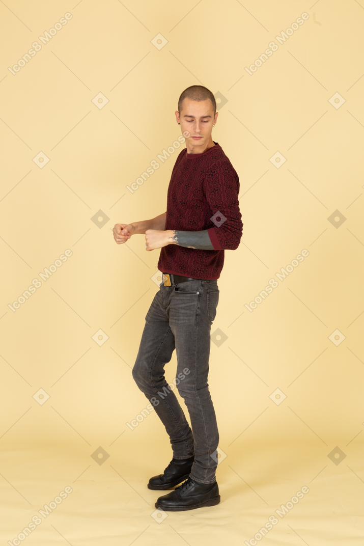 Вид сбоку на молодого человека в красном пуловере, сжимающего кулаки