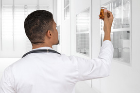Back view of a doctor holding a pill bottle