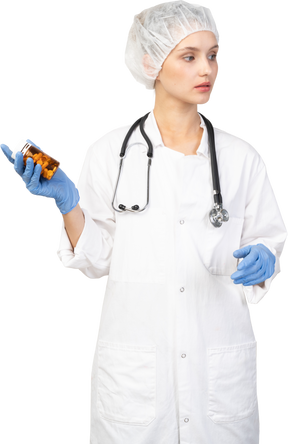 Vue de face d'une jeune femme médecin tenant un pot de pilules