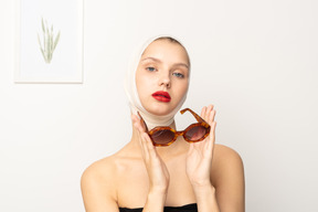 Young woman with bandaged head holding sunglasses