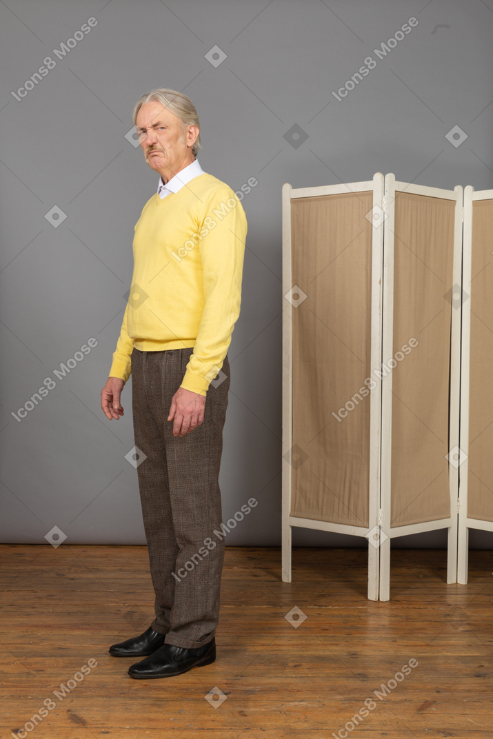 Vista de tres cuartos de un anciano disgustado mirando a la cámara