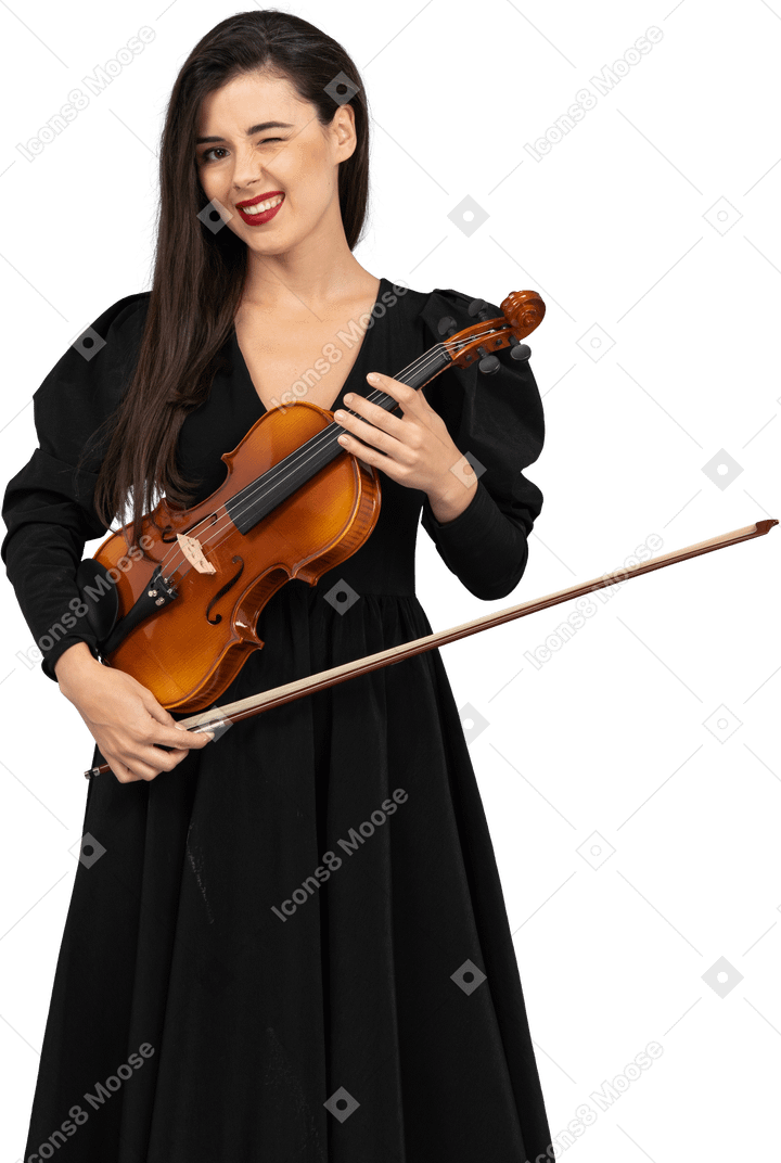 バイオリンを保持している黒いドレスを着た陽気な若い女性のクローズアップ