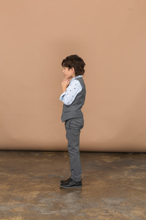 Vista lateral de um menino pensativo de terno cinza