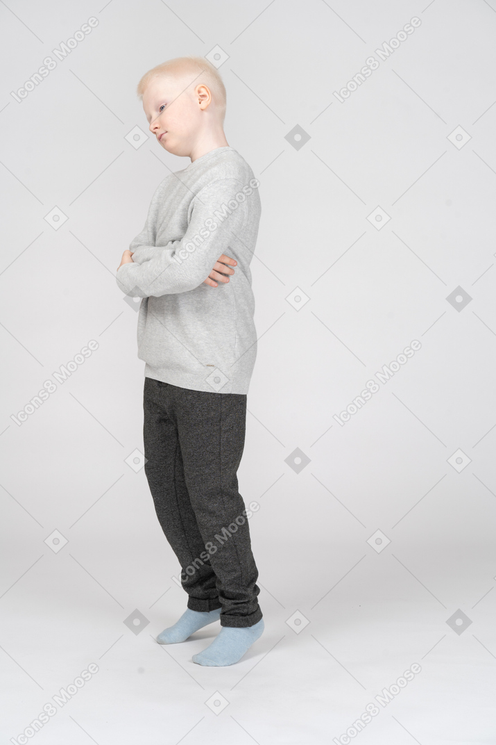 Vista de três quartos de um garoto travesso balançando a cabeça enquanto cruza as mãos