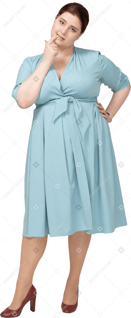 Front view of a woman in blue dress biting her finger