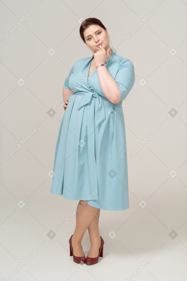 Вид спереди женщины в синем платье, кусающей палец