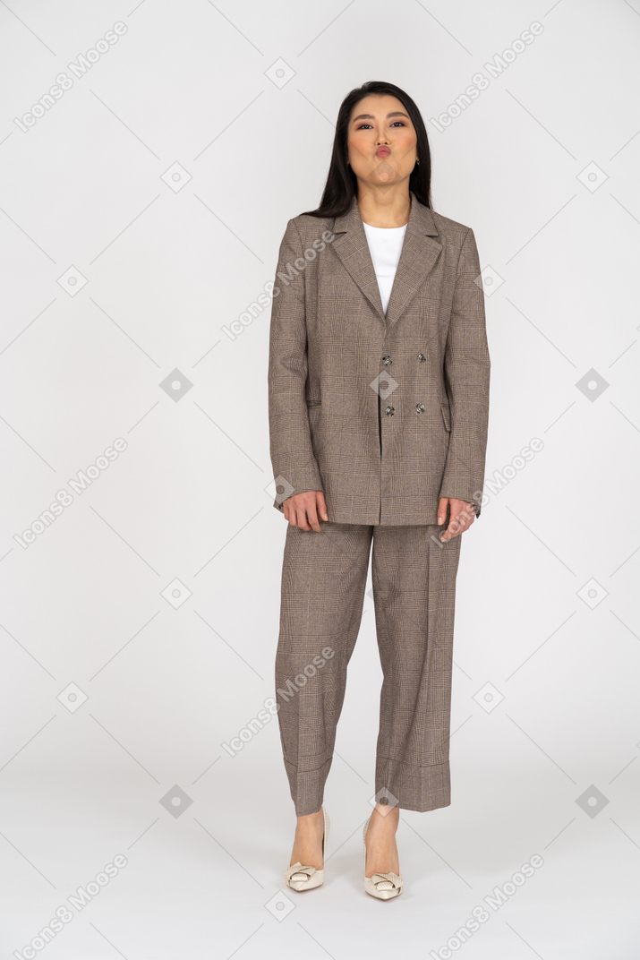 茶色のビジネススーツを着たふくれっ面の若い女性の正面図。頭を上げながら