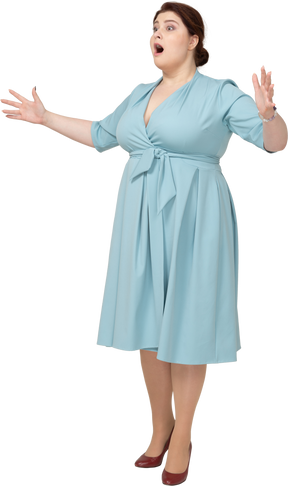Vista frontal de uma mulher chocada em um vestido azul olhando para a câmera