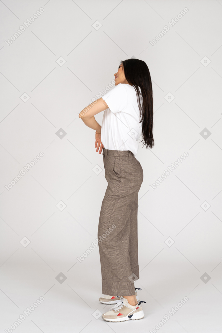 Vista lateral de uma jovem inclinando-se de calça e camiseta