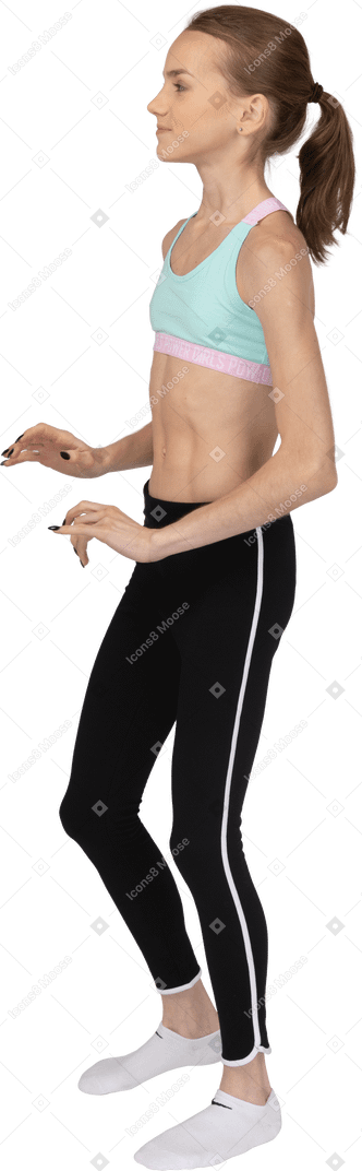 Side view of a cute teen girl in sportswear stepping aside and raising hands